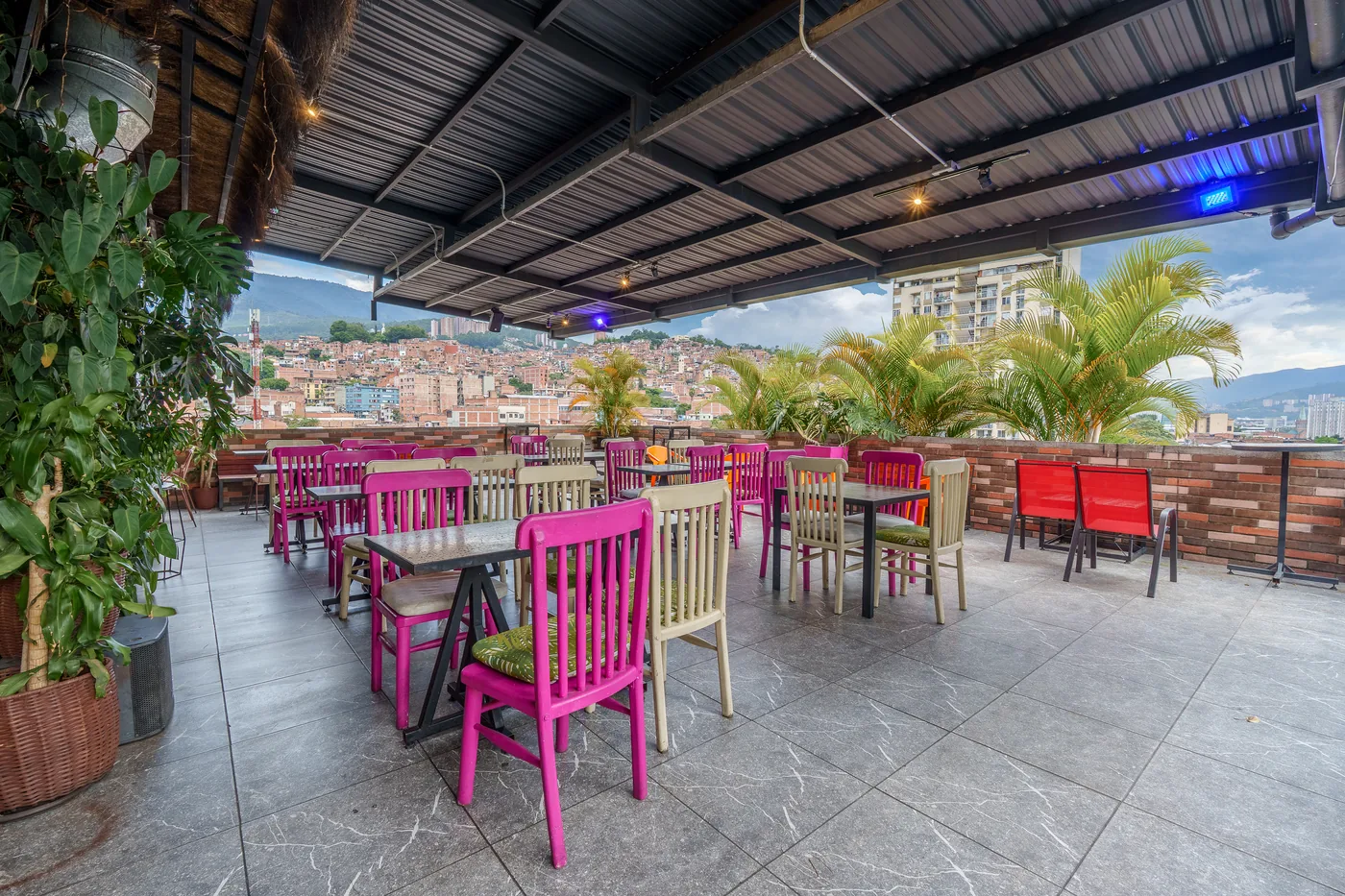 Terraza del rooftop al atardecer, con sillas de colores y luces colgantes